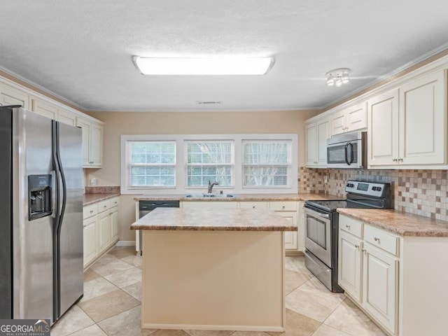 kitchen featuring tasteful backsplash, a kitchen island, light tile floors, stainless steel appliances, and sink