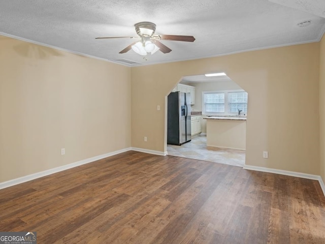 empty room with ceiling fan, a textured ceiling, light hardwood / wood-style flooring, and crown molding