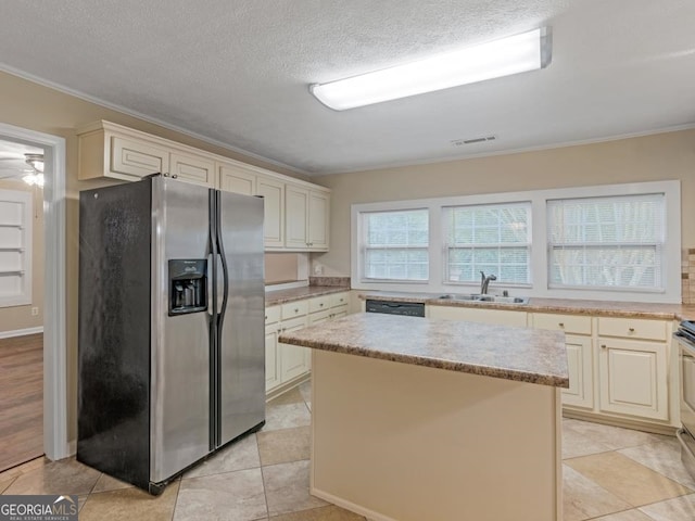 kitchen with appliances with stainless steel finishes, a kitchen island, light tile floors, ceiling fan, and sink