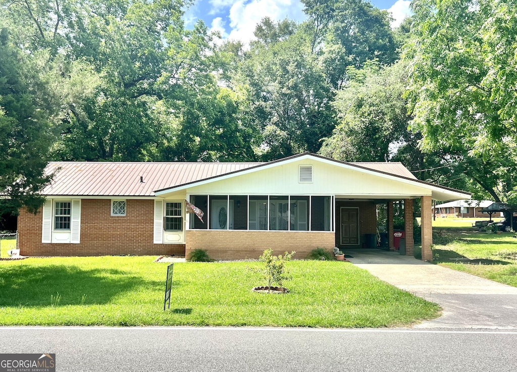 single story home with a carport, a sunroom, and a front yard