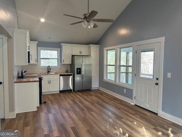 kitchen featuring butcher block counters, sink, vaulted ceiling, white cabinets, and appliances with stainless steel finishes