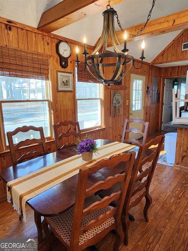 dining area with lofted ceiling with beams, a chandelier, electric panel, wood walls, and hardwood / wood-style floors