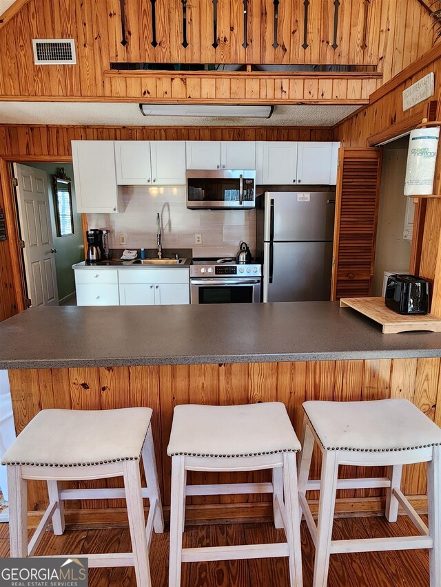 kitchen with white cabinets, a breakfast bar area, stainless steel appliances, and sink