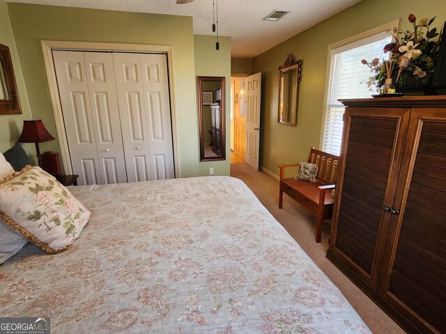 carpeted bedroom featuring a textured ceiling, ceiling fan, and a closet