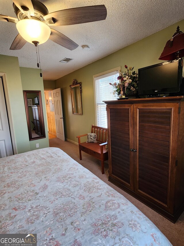 carpeted bedroom with ceiling fan and a textured ceiling