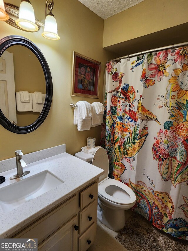 bathroom featuring a textured ceiling, walk in shower, vanity, and toilet