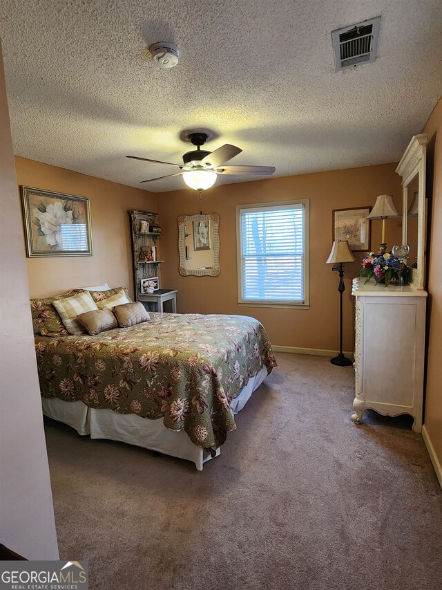 carpeted bedroom featuring ceiling fan and a textured ceiling