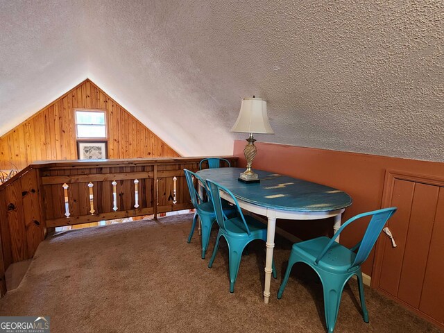 dining room with a textured ceiling, wooden walls, lofted ceiling, and carpet flooring