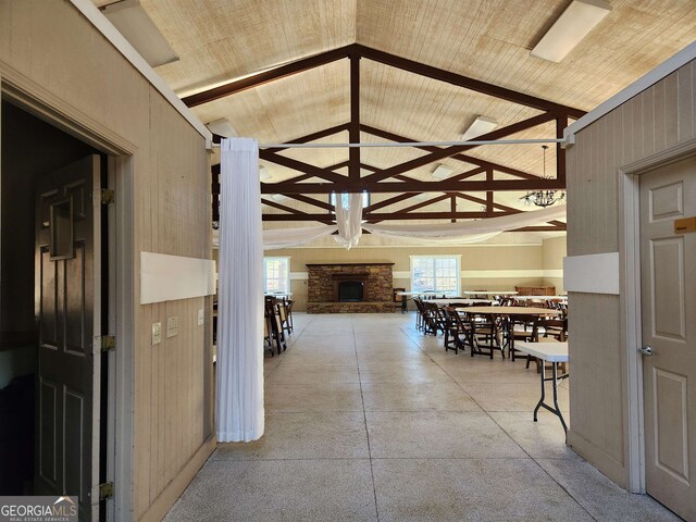 hall featuring wooden walls, wood ceiling, and high vaulted ceiling