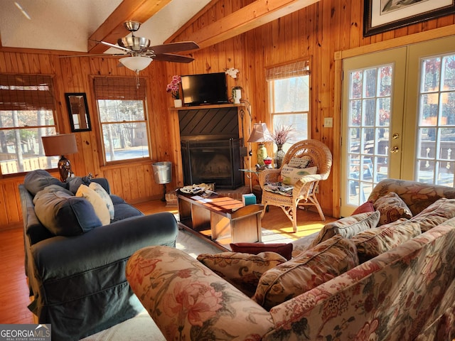 living room with ceiling fan, wood-type flooring, french doors, wooden walls, and lofted ceiling with beams