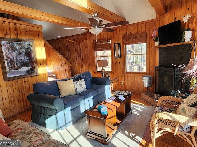 living room featuring lofted ceiling with beams, wood walls, ceiling fan, and light hardwood / wood-style floors