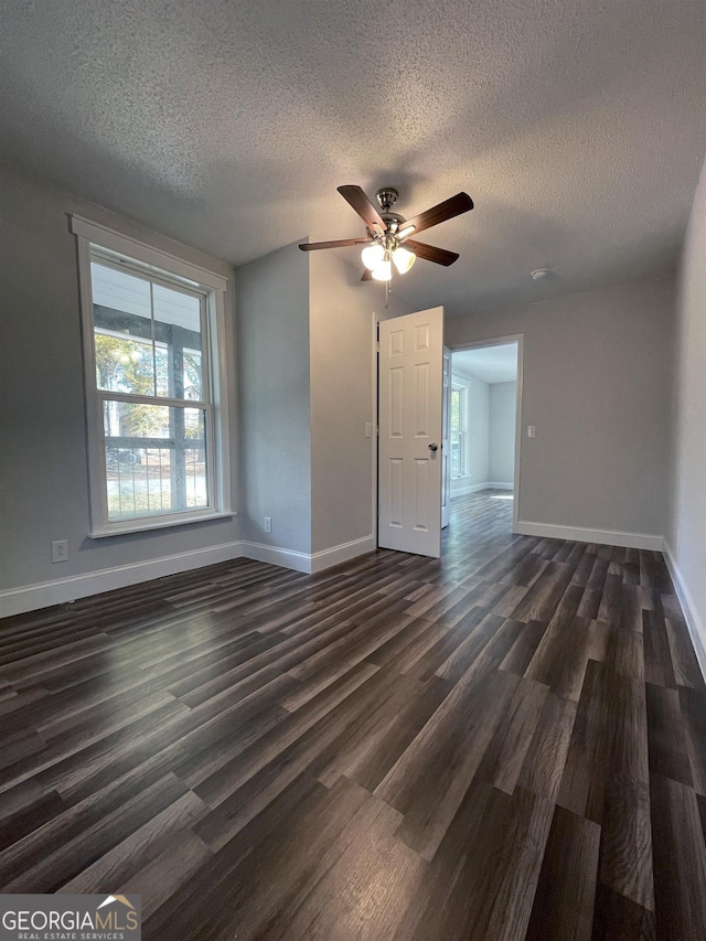 unfurnished living room featuring dark wood-type flooring, ceiling fan, and a textured ceiling