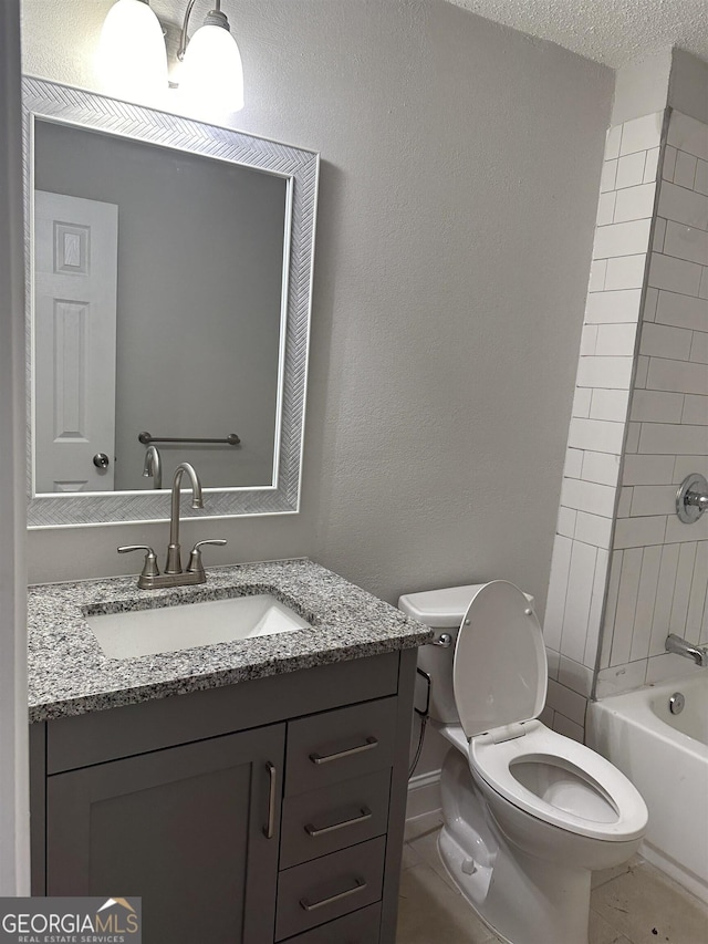 full bathroom with vanity, toilet, tiled shower / bath combo, and a textured ceiling