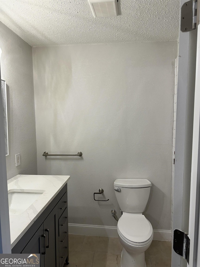 bathroom featuring tile patterned flooring, vanity, a textured ceiling, and toilet