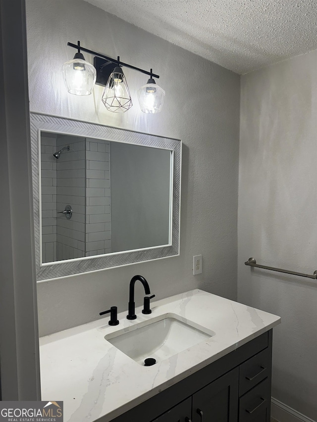 bathroom featuring vanity, a tile shower, and a textured ceiling