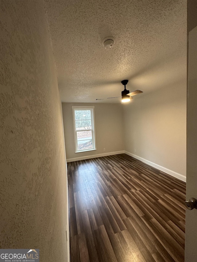 unfurnished room featuring ceiling fan, dark hardwood / wood-style flooring, and a textured ceiling