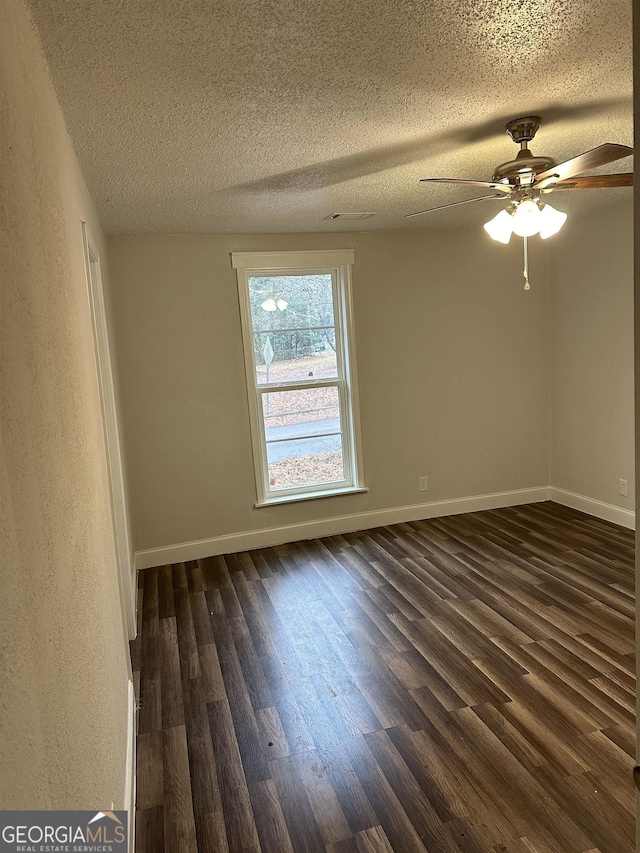 unfurnished room with ceiling fan, dark wood-type flooring, and a textured ceiling