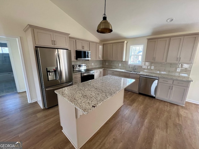 kitchen featuring appliances with stainless steel finishes, a kitchen island, hanging light fixtures, and decorative backsplash