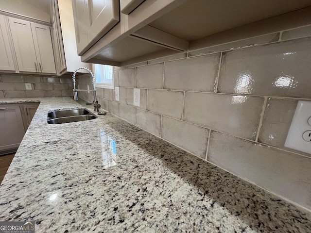 kitchen with sink, backsplash, and light stone countertops