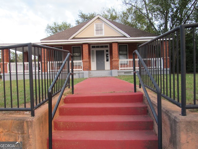 view of front of home with covered porch and a front lawn