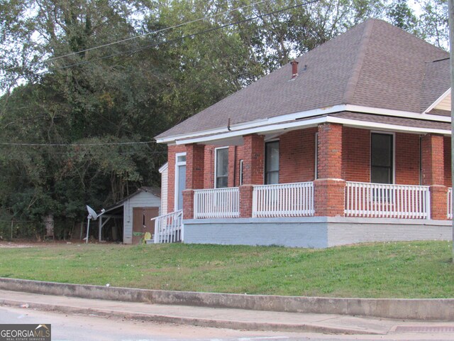4154 Houston Ave, Macon, GA 31206 - bungalow-style home with covered porch, a shingled roof, brick siding, and a storage unit