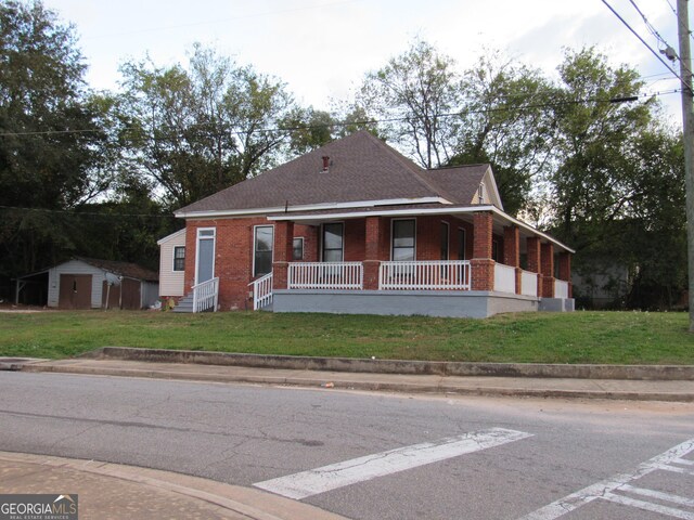 4154 Houston Ave, Macon, GA 31206 - view of front of home featuring covered porch, a front lawn, a storage unit, and brick siding