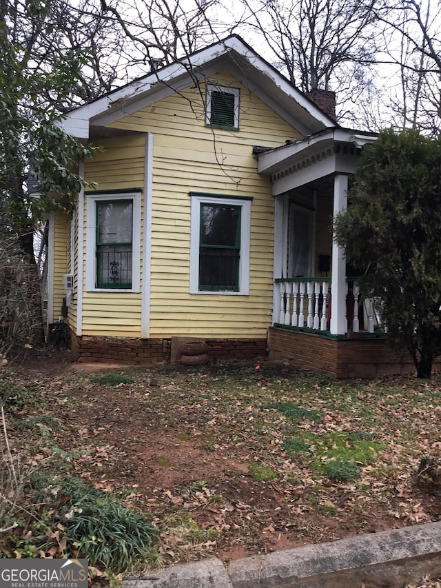 view of side of home featuring covered porch