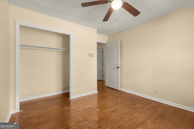 unfurnished bedroom with a closet, ceiling fan, a textured ceiling, and dark wood-type flooring