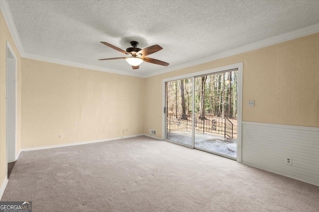 carpeted spare room featuring ceiling fan, a textured ceiling, and crown molding