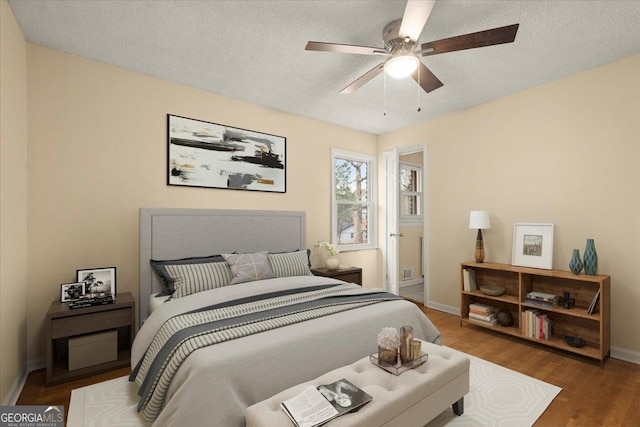 bedroom featuring ceiling fan, dark wood-type flooring, and a textured ceiling