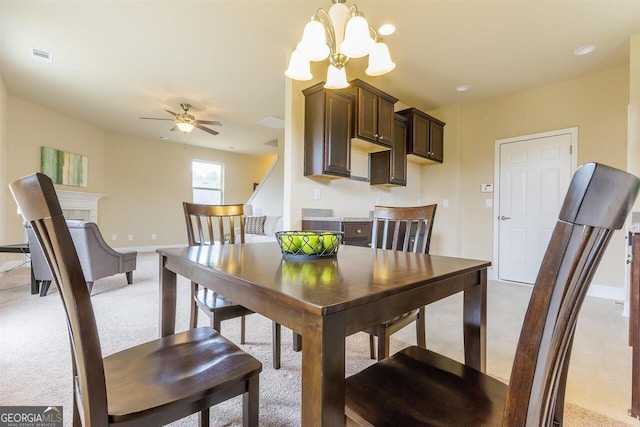 dining space with light colored carpet and ceiling fan with notable chandelier