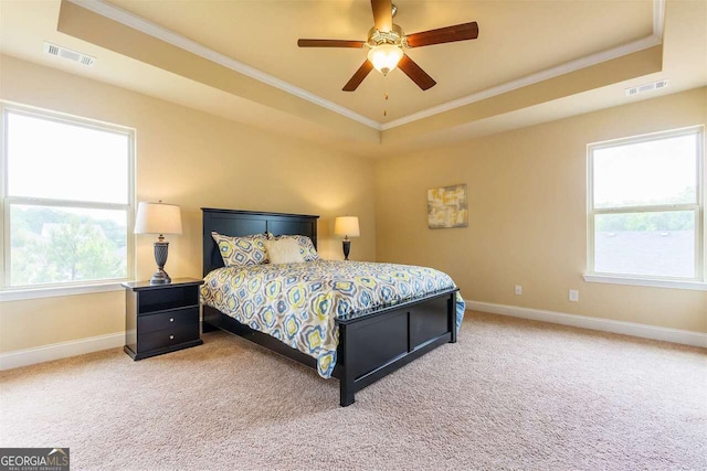 carpeted bedroom with crown molding, a tray ceiling, and ceiling fan