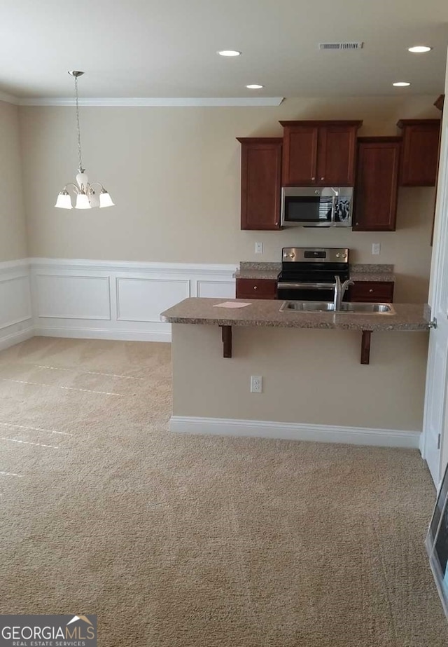 kitchen with an inviting chandelier, stainless steel appliances, light carpet, and dark stone countertops