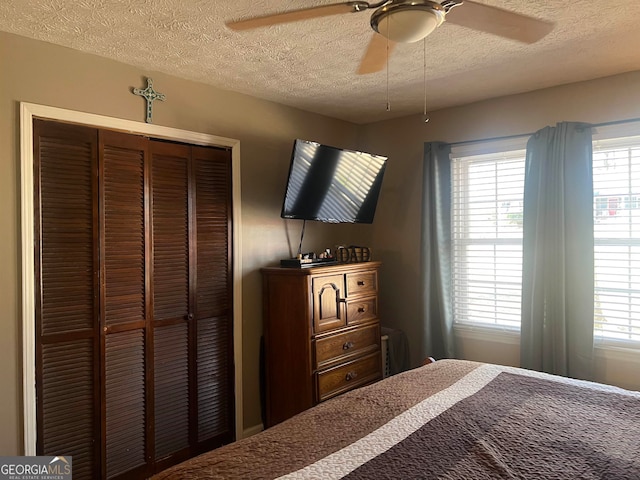 bedroom with a textured ceiling, ceiling fan, and a closet