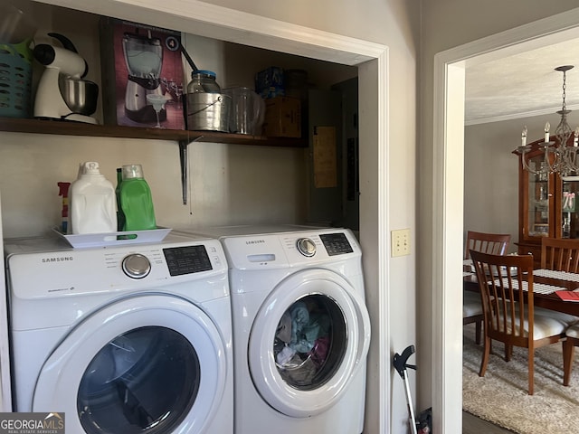 laundry area with washing machine and dryer and a notable chandelier