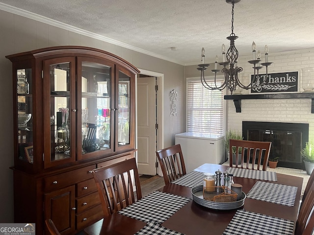 dining area with an inviting chandelier, a fireplace, wood-type flooring, ornamental molding, and a textured ceiling