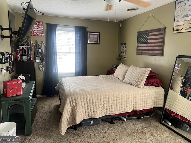 carpeted bedroom featuring ceiling fan and a textured ceiling