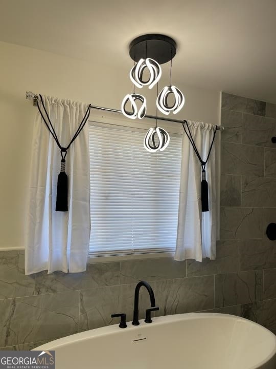 bathroom featuring a notable chandelier and a bath