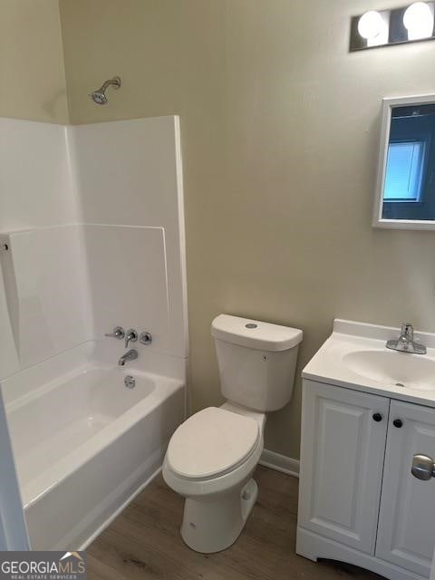 full bathroom featuring shower / bath combination, wood-type flooring, vanity with extensive cabinet space, and toilet