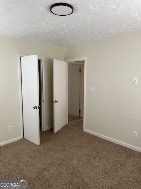 unfurnished bedroom with light colored carpet and a textured ceiling