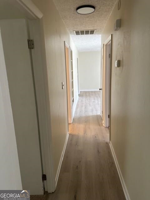 hall featuring a textured ceiling and light hardwood / wood-style flooring