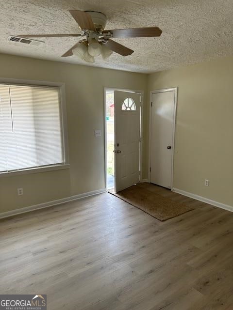 foyer featuring a textured ceiling, ceiling fan, and light wood-type flooring