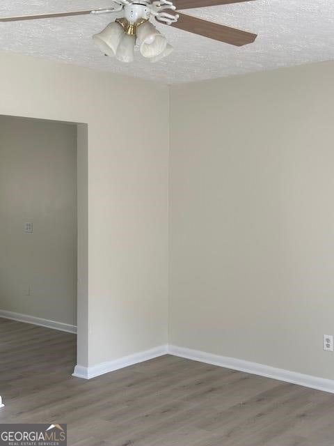 unfurnished room with ceiling fan, a textured ceiling, and dark hardwood / wood-style flooring