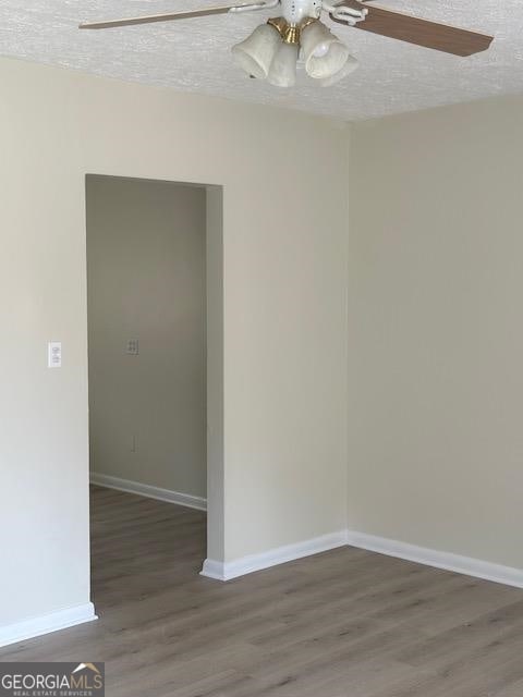 unfurnished room featuring ceiling fan, hardwood / wood-style floors, and a textured ceiling