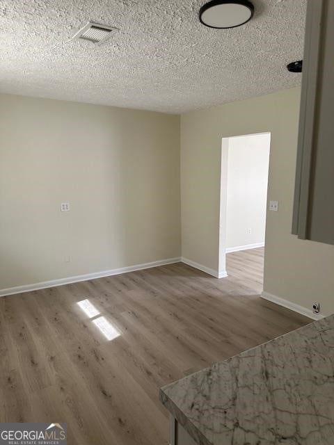 spare room with dark hardwood / wood-style floors and a textured ceiling