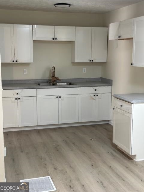 kitchen featuring white cabinets, sink, and light hardwood / wood-style floors