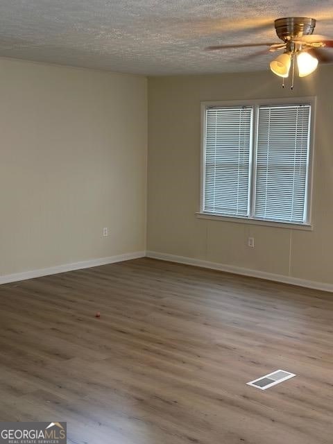 empty room featuring a textured ceiling, ceiling fan, and light wood-type flooring