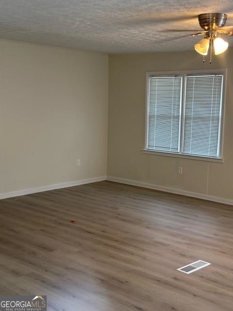 spare room with a textured ceiling, light hardwood / wood-style floors, and ceiling fan