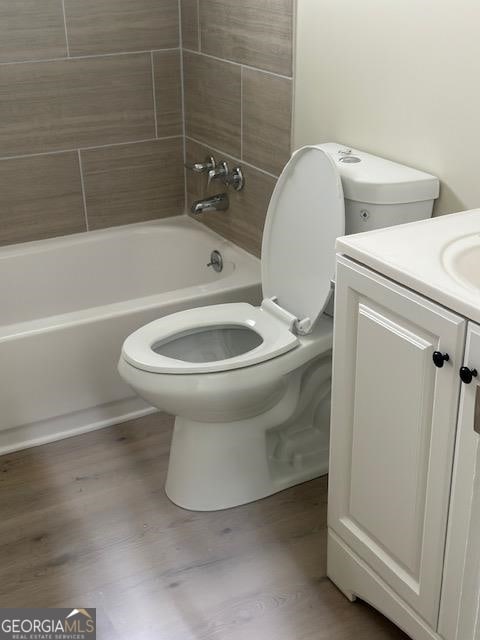 full bathroom with tiled shower / bath combo, vanity, wood-type flooring, and toilet