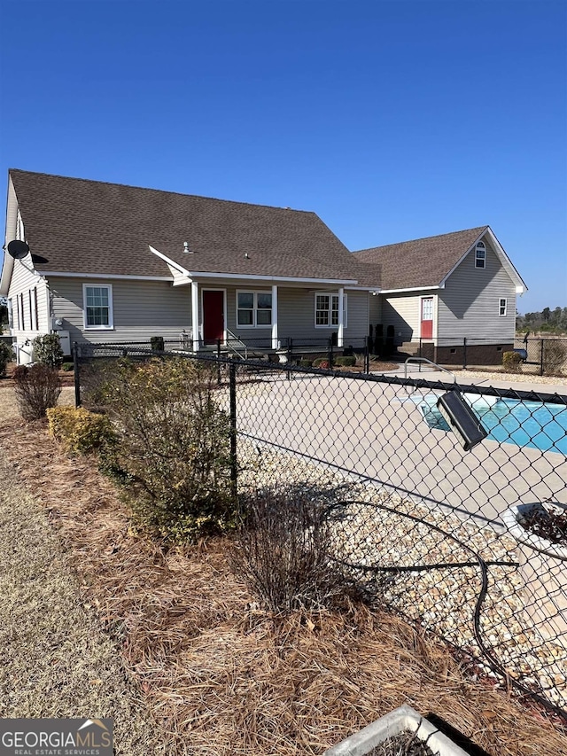 rear view of house featuring a covered pool and a patio